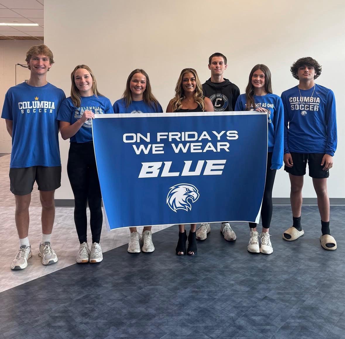 Columbia students holding an On Fridays We Wear Blue school spirit sign